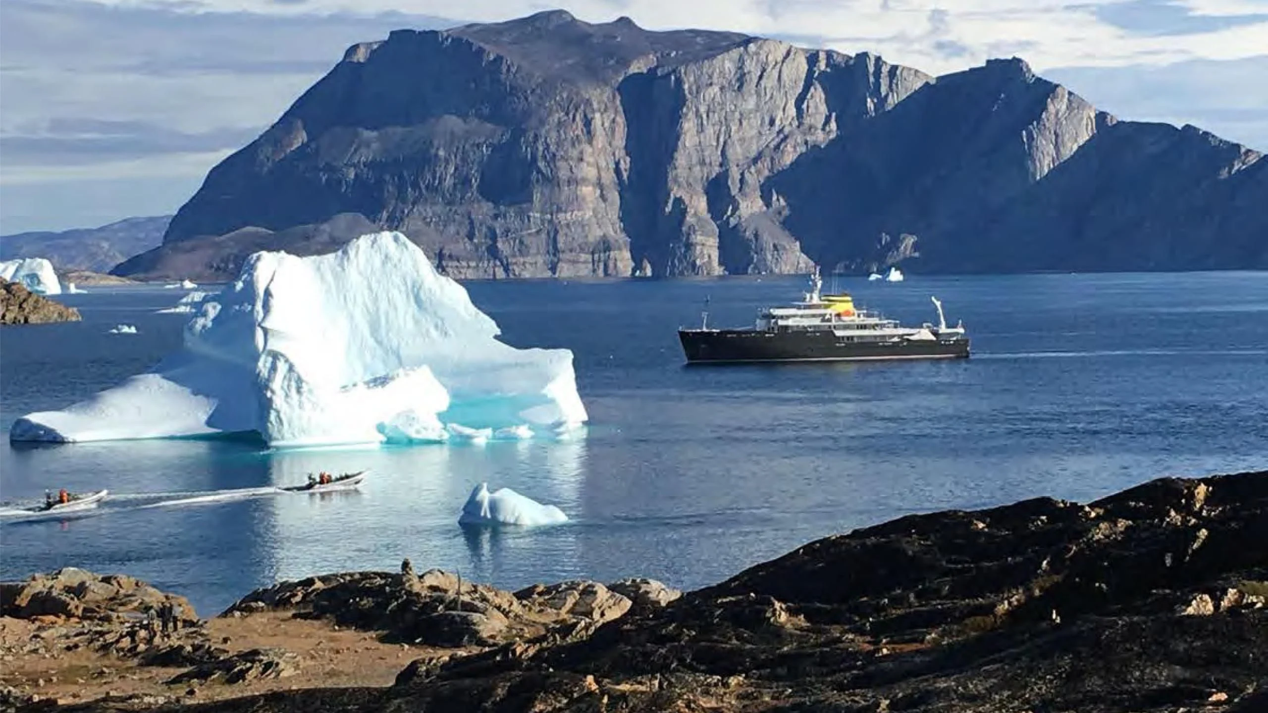 a boat in the water near a large iceberg aboard YERSIN Yacht for Charter