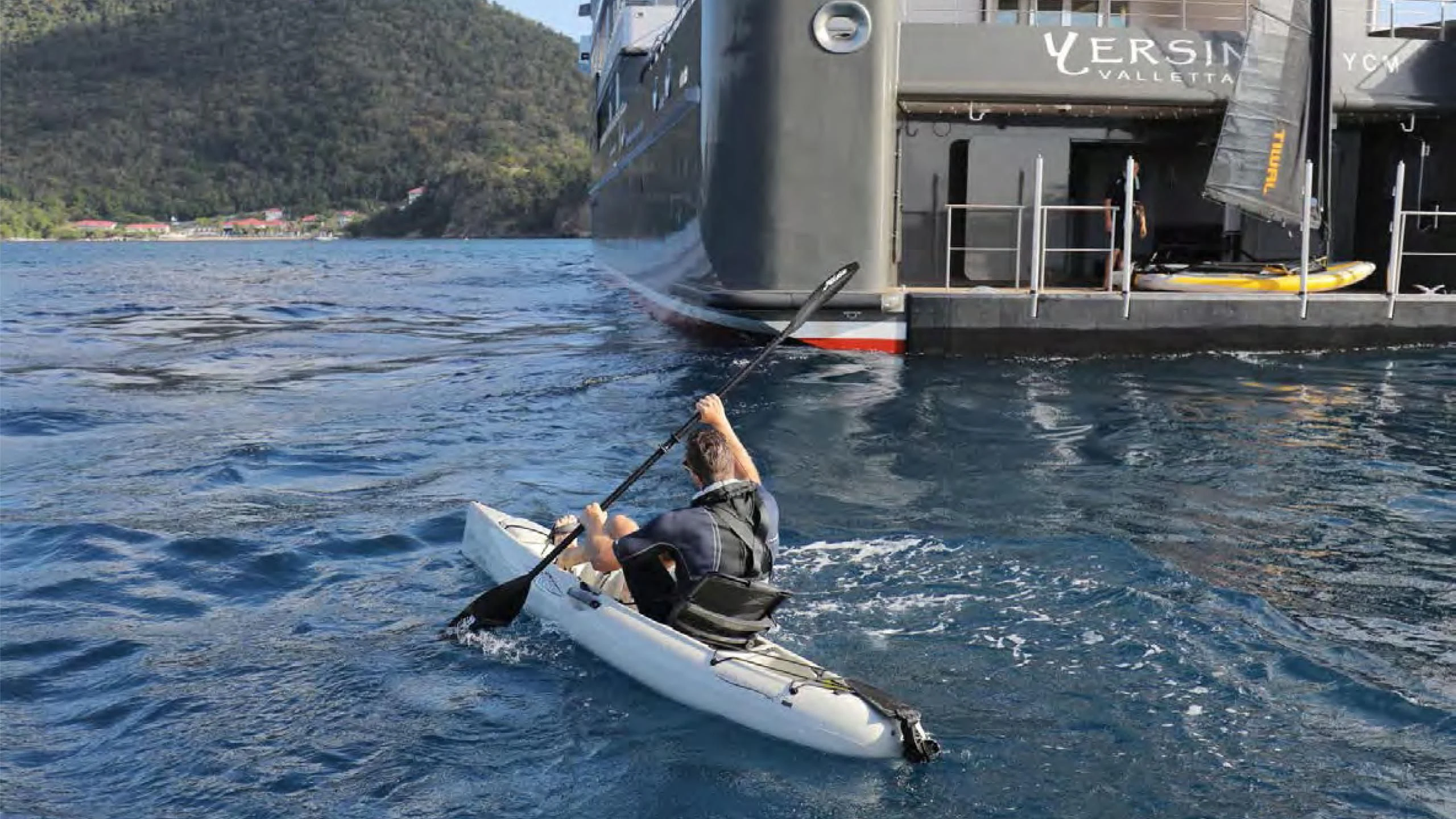 a person in a kayak paddling on water aboard YERSIN Yacht for Charter