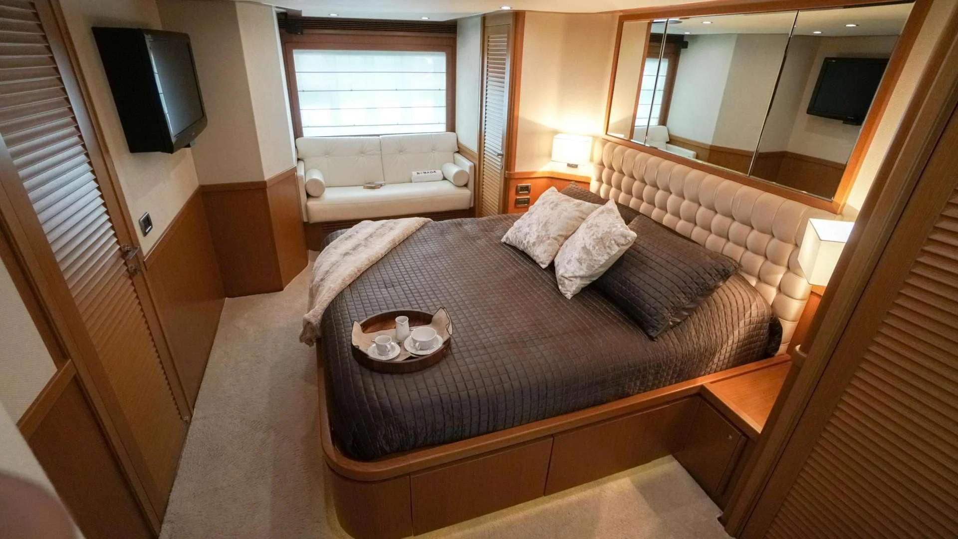 a bedroom with a bed and a television aboard NOMADA Yacht for Charter