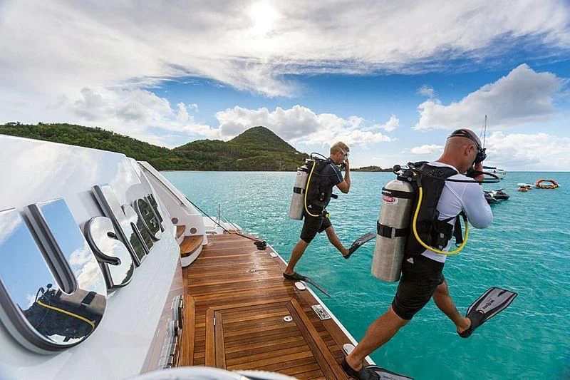 a couple of people walking on a dock with a boat in the water aboard USHER Yacht for Sale