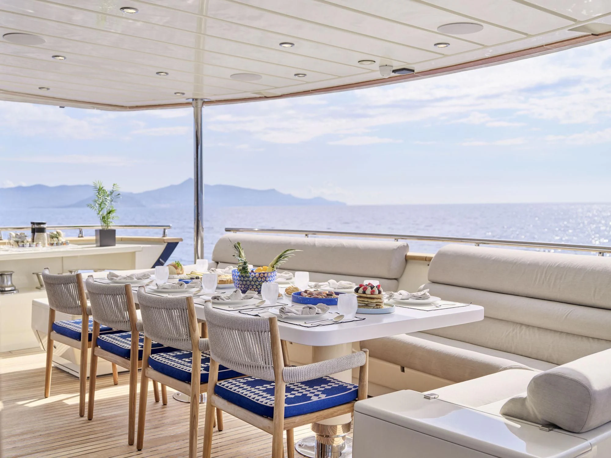 a table set for a meal on a balcony overlooking the ocean aboard BEYOND Yacht for Charter
