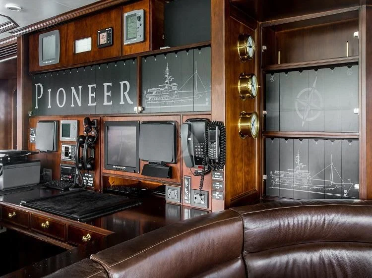 a leather couch in front of a desk with a computer on it aboard PIONEER Yacht for Sale