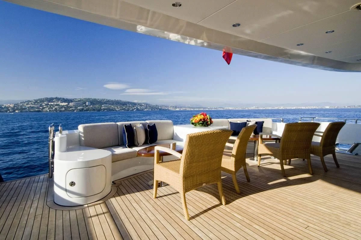 a room with a couch and chairs on a deck overlooking a body of water aboard KIJO Yacht for Sale