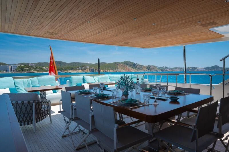 a table set for a meal on a deck overlooking a body of water aboard KIA ORA Yacht for Sale