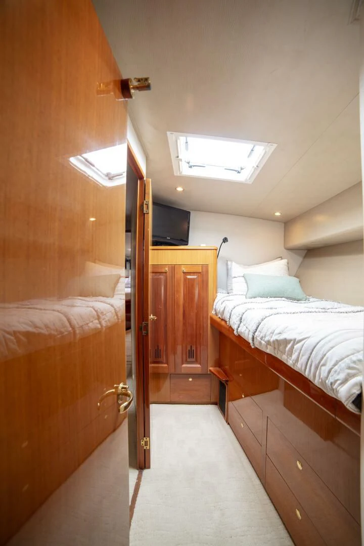a bedroom with a bed and a television aboard PRIME TIME Yacht for Sale