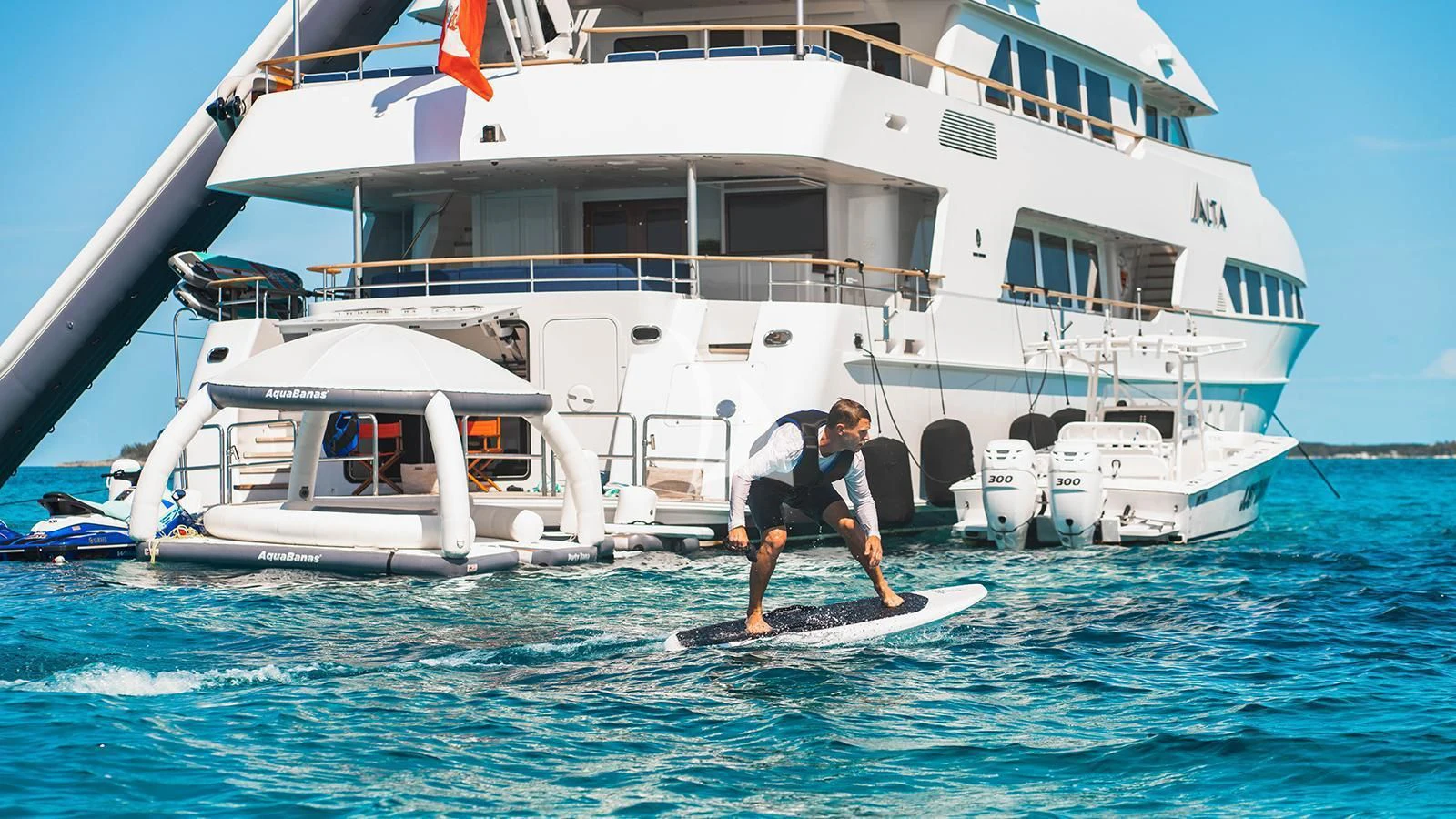 a person on a surfboard in front of a boat aboard ALTA Yacht for Sale