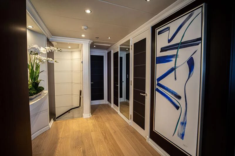 a hallway with a blue door and white walls aboard ALTA Yacht for Sale