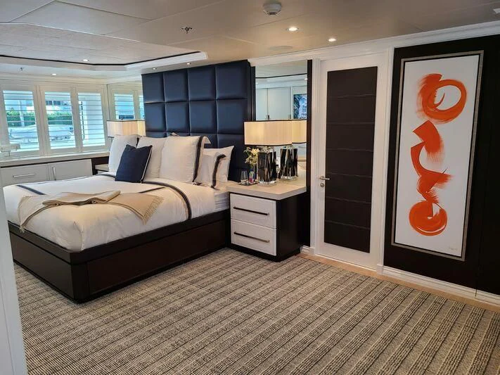a bedroom with a bed and a painting on the wall aboard ALTA Yacht for Sale