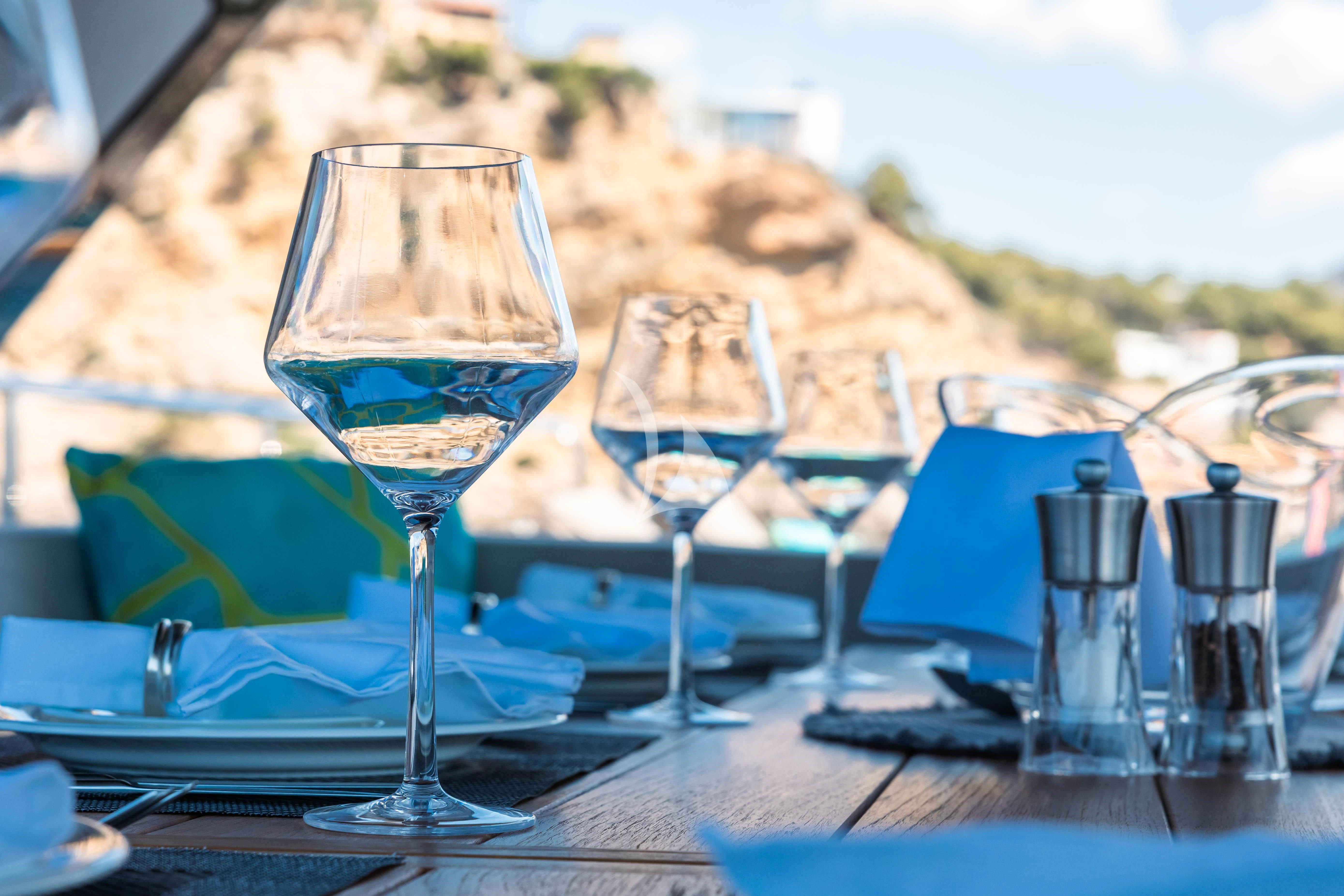 a table with wine glasses and a view of the mountains aboard MOONLIGHT Yacht for Sale