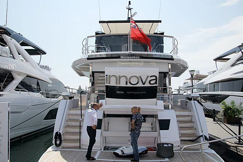 a couple of men standing on a boat with a flag on the front aboard MOONLIGHT Yacht for Sale