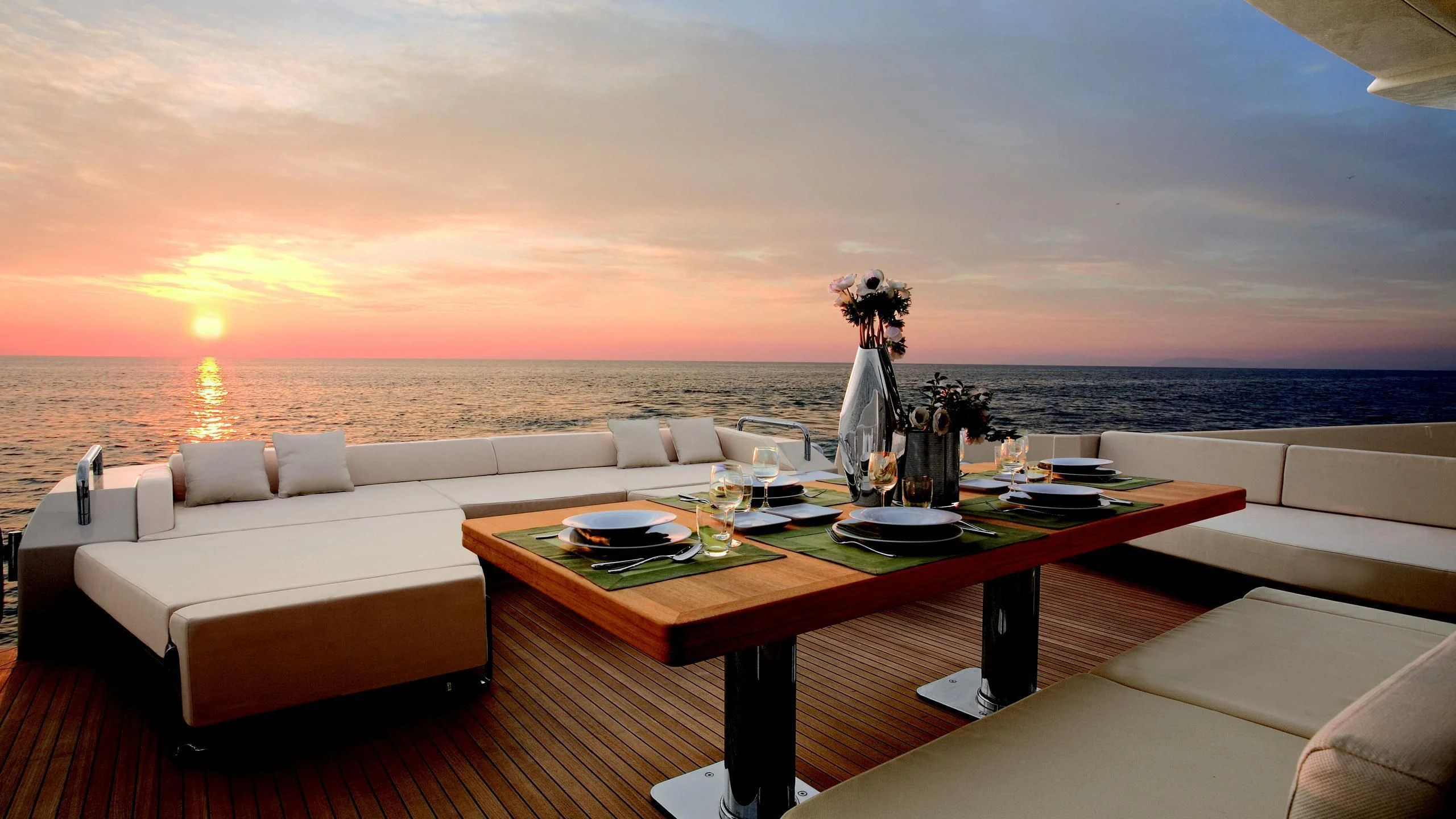 a table with a large white couch and a large body of water in the background aboard DUKE Yacht for Sale