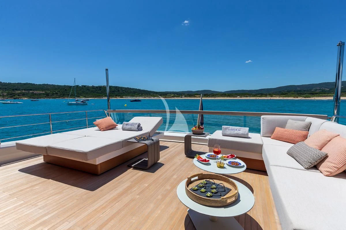 a room with a bed and a table on a balcony overlooking a body of water aboard VINCI II Yacht for Sale