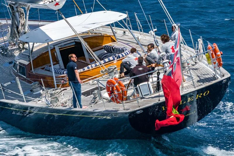 a person standing on a boat with a flag on the front aboard BOLERO Yacht for Sale