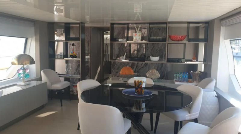 a room with a table chairs and shelves with objects on the shelves aboard HANAVA Yacht for Sale