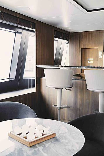 a table with a lamp and a chair in a room with wood cabinets aboard BACCHANAL Yacht for Sale