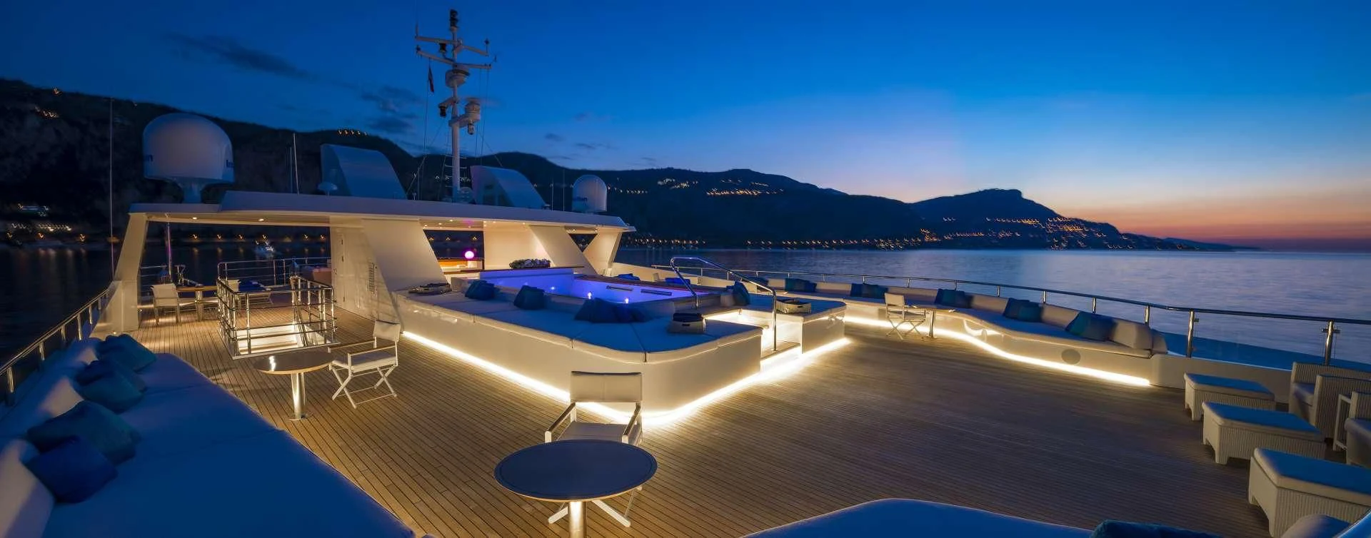 a pool with a deck and a view of a city at night aboard MARQUISE Yacht for Sale