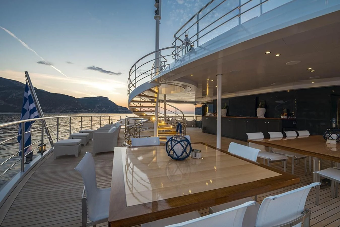 a deck with a railing and a railing with a railing and a body of water and mountains in aboard MARQUISE Yacht for Sale