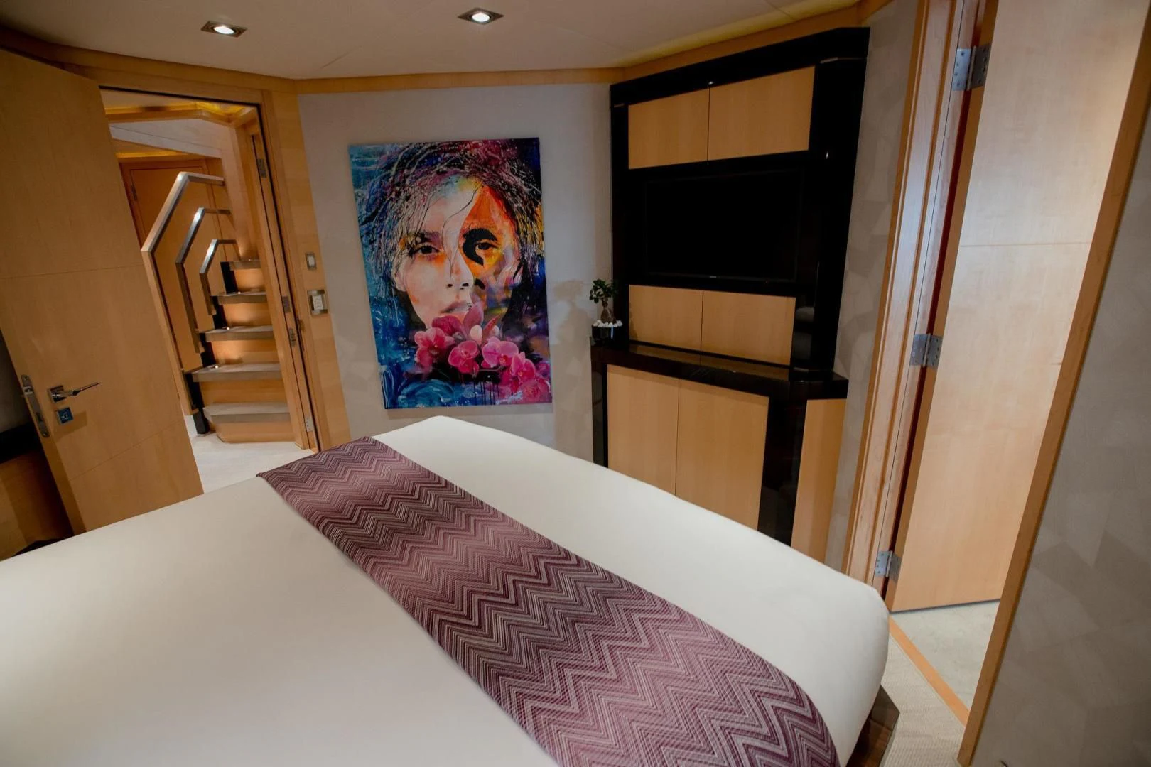 a bed with a painting on the wall aboard KJOS Yacht for Charter