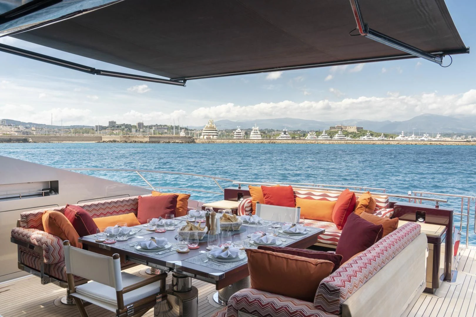 a table set for a meal on a balcony overlooking a large body of water aboard KJOS Yacht for Charter