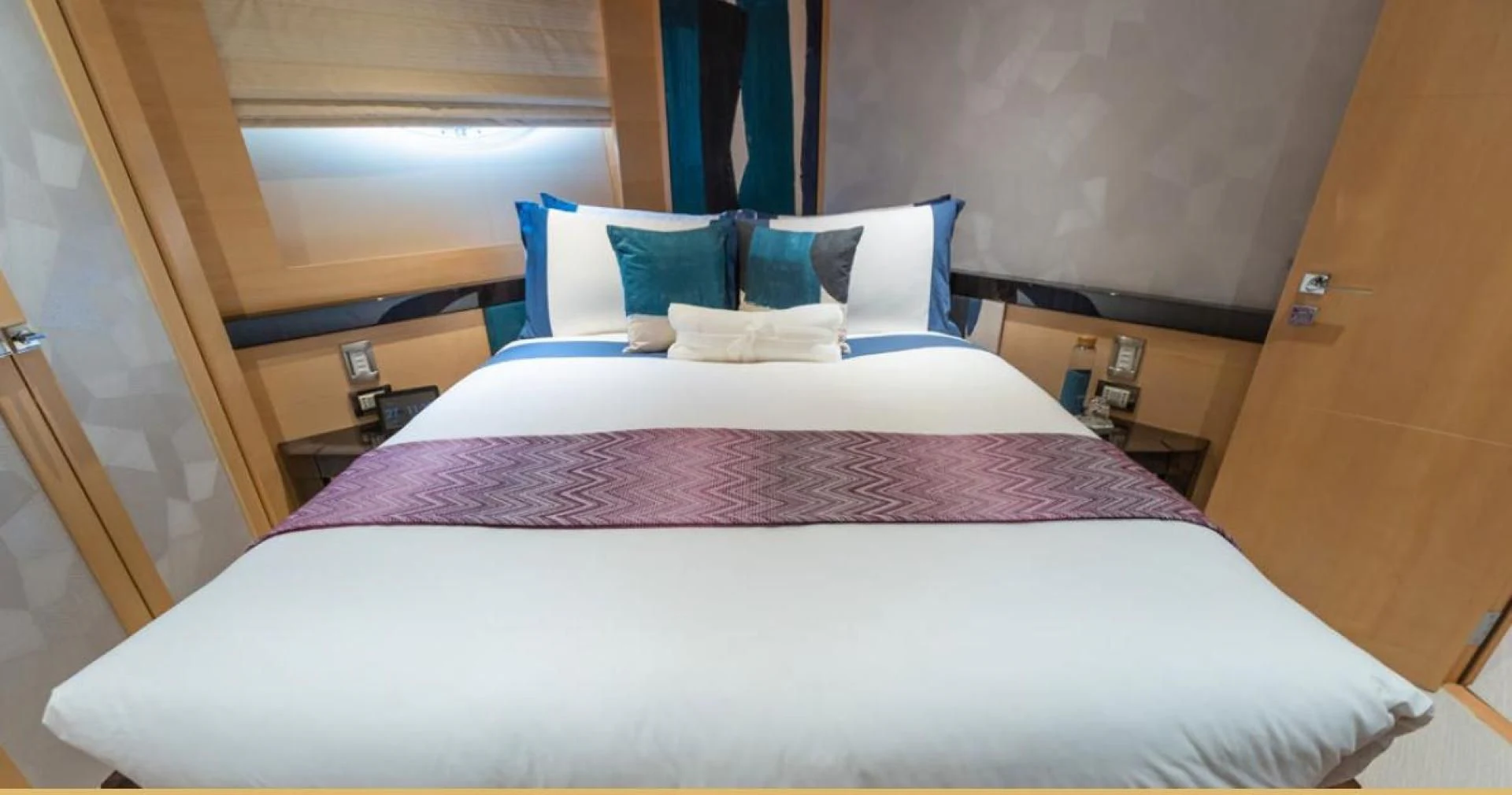 a bed with a purple comforter aboard KJOS Yacht for Charter