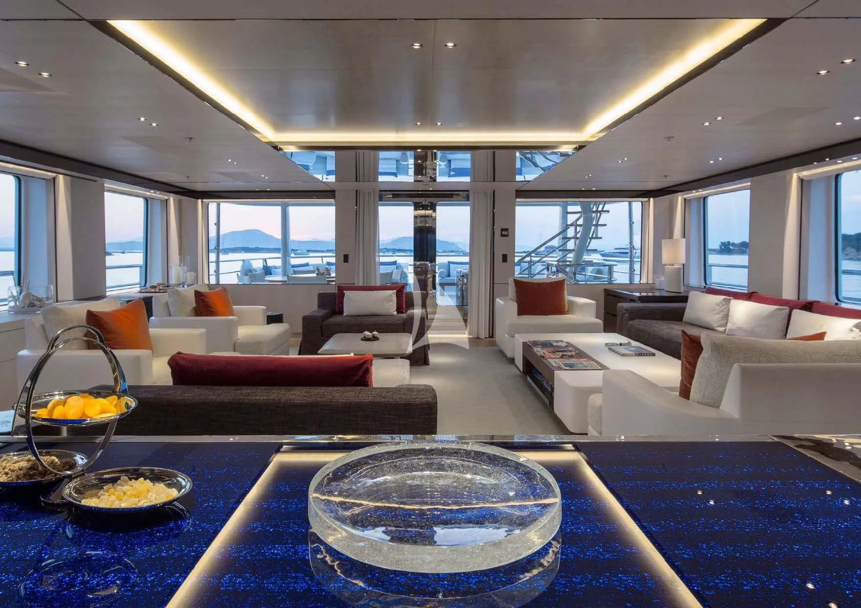 a living room with a large blue table and white couches aboard KAMALAYA Yacht for Sale