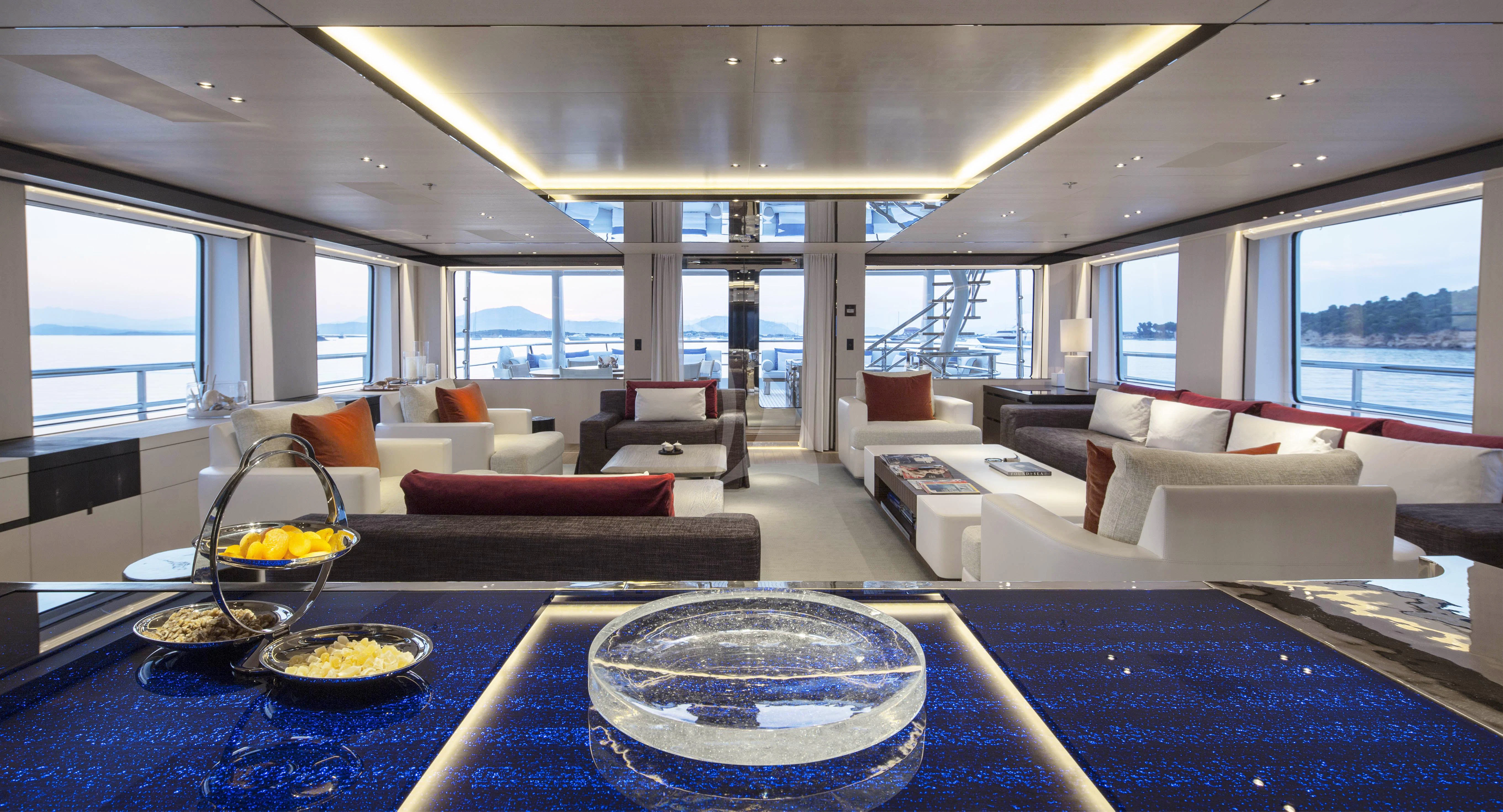 a living room with a large blue table and white couches aboard KAMALAYA Yacht for Sale