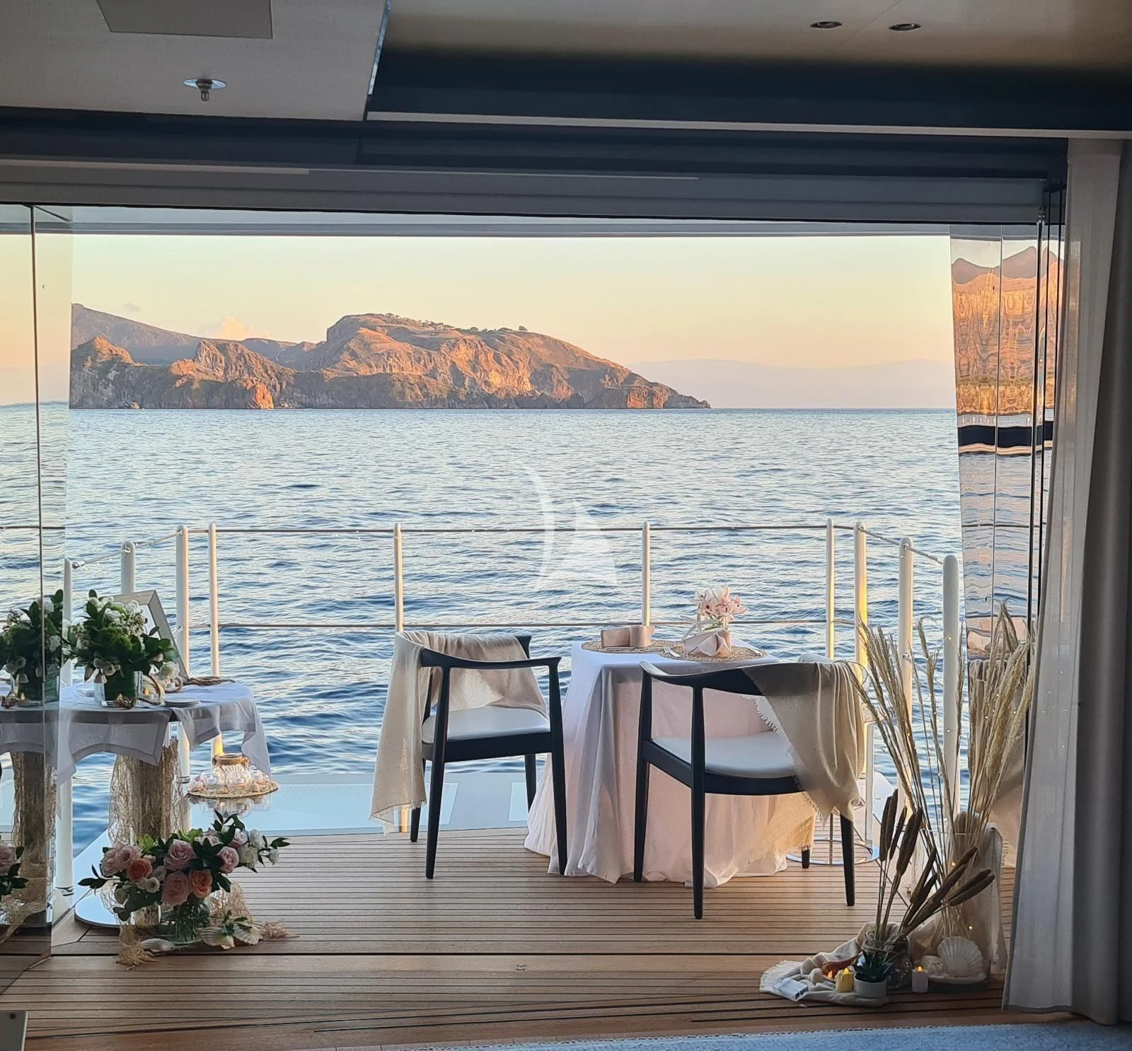 a room with a table and chairs and a view of the mountains aboard KAMALAYA Yacht for Sale