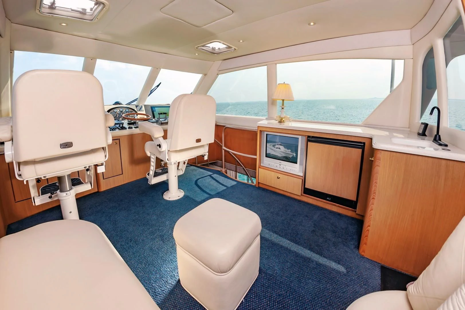 a room with a blue rug and white chairs and a television aboard DOG HOUSE Yacht for Sale