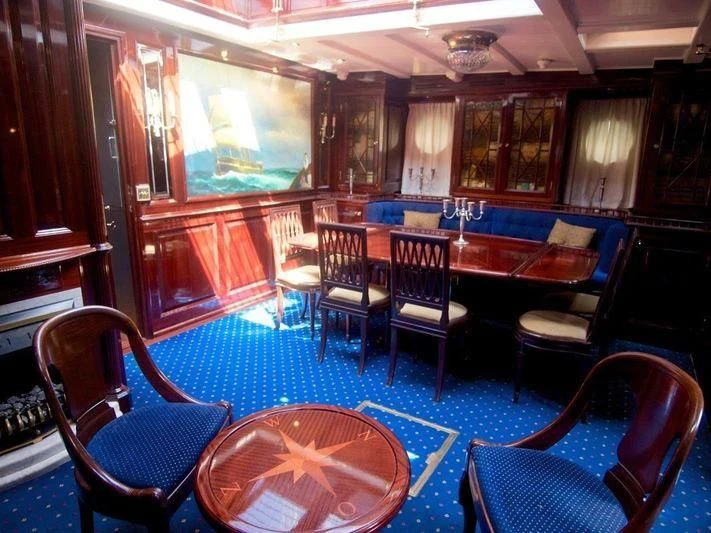 a room with a table chairs and a rug aboard DORIANA Yacht for Sale