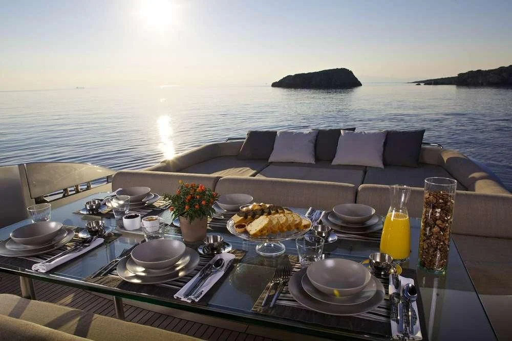 a table with food and drinks on it by a large body of water aboard SOLARIS Yacht for Sale