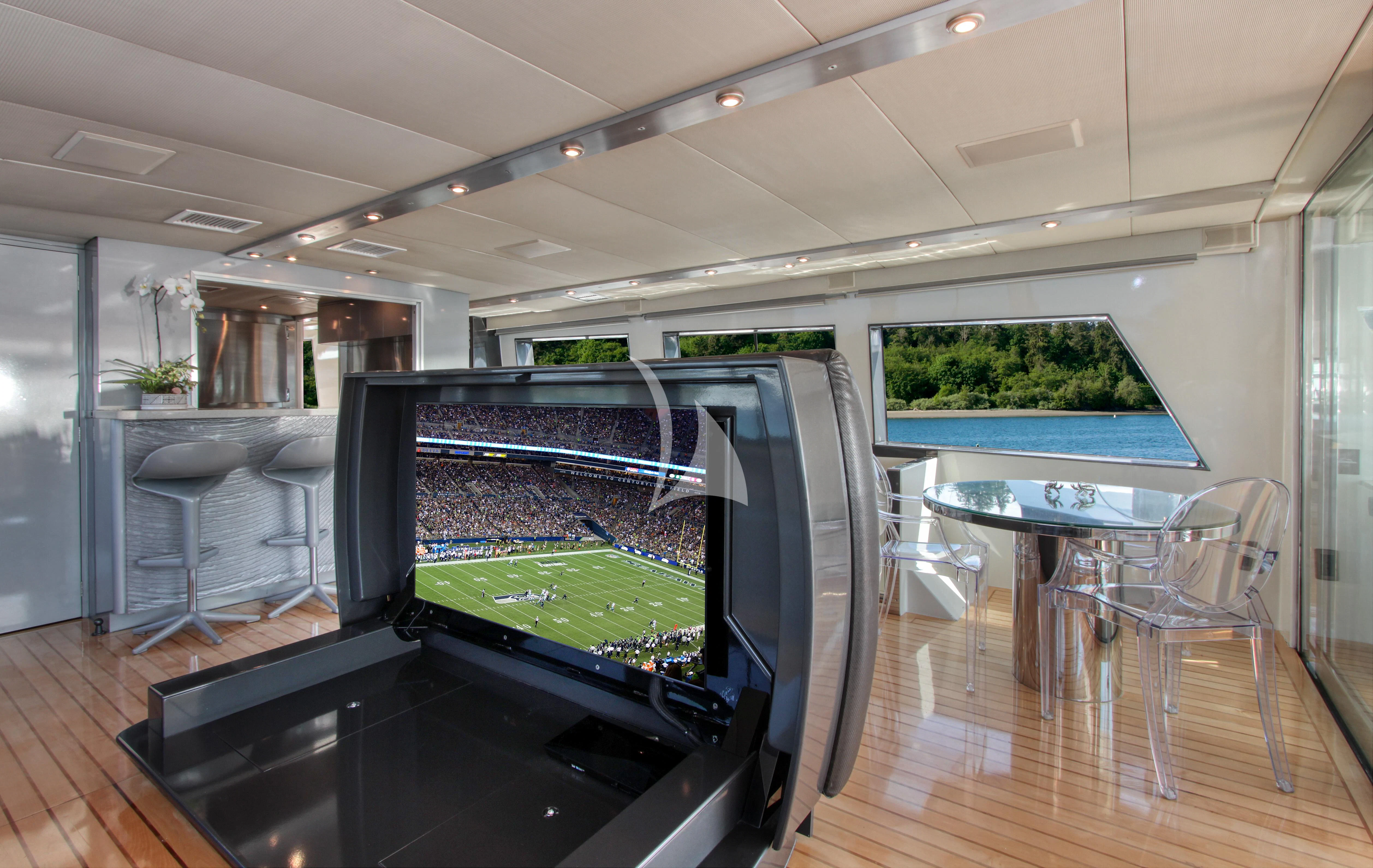 a large room with a large glass table and a large screen aboard FIRST HOME Yacht for Sale