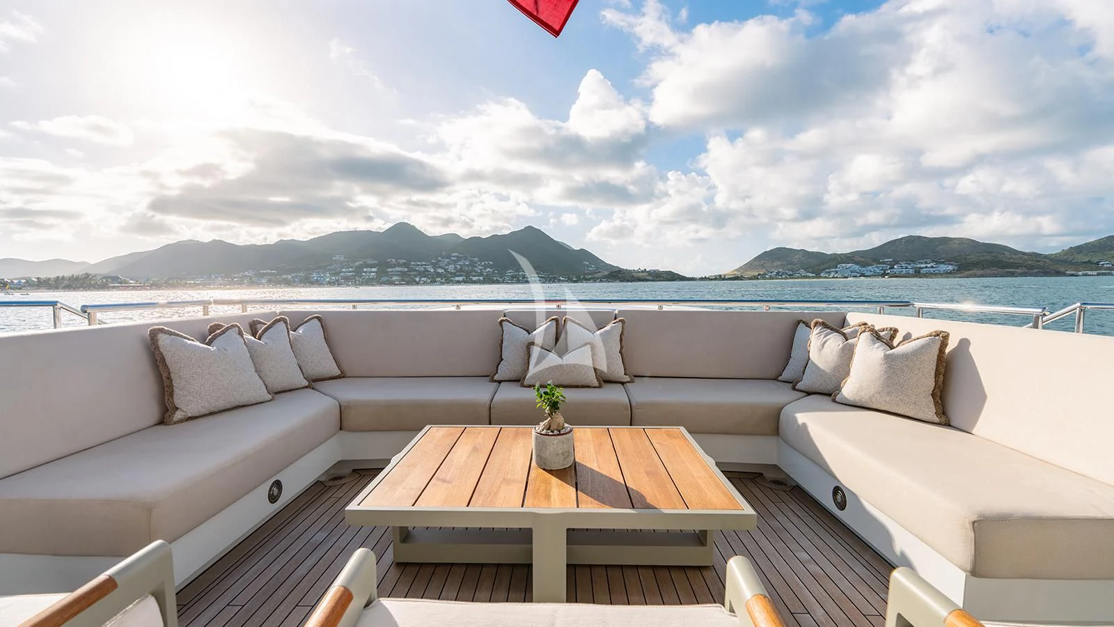 a table on a deck with a view of the ocean and mountains in the background aboard MOSKITO Yacht for Sale