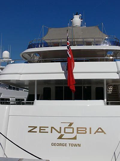 a large white boat with a red flag on the front aboard ZENOBIA Yacht for Sale