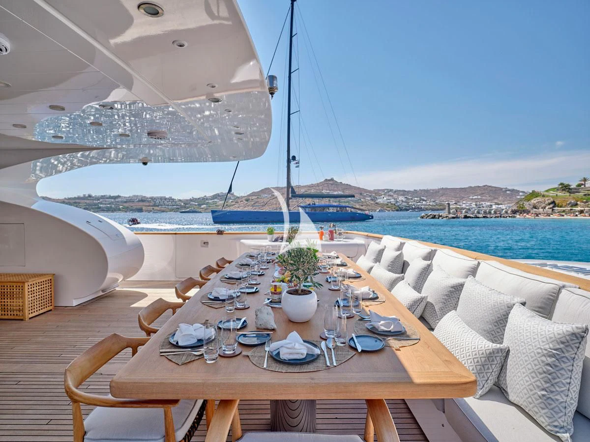 a table set for a meal on a balcony overlooking a body of water aboard WHITE KNIGHT Yacht for Sale