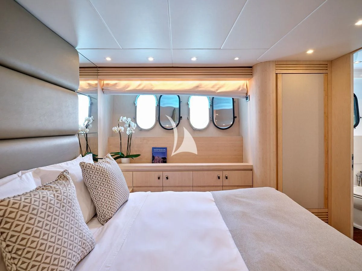 a bed with a white sheet and pillows in a room with a wood door and a mirror aboard WHITE KNIGHT Yacht for Sale