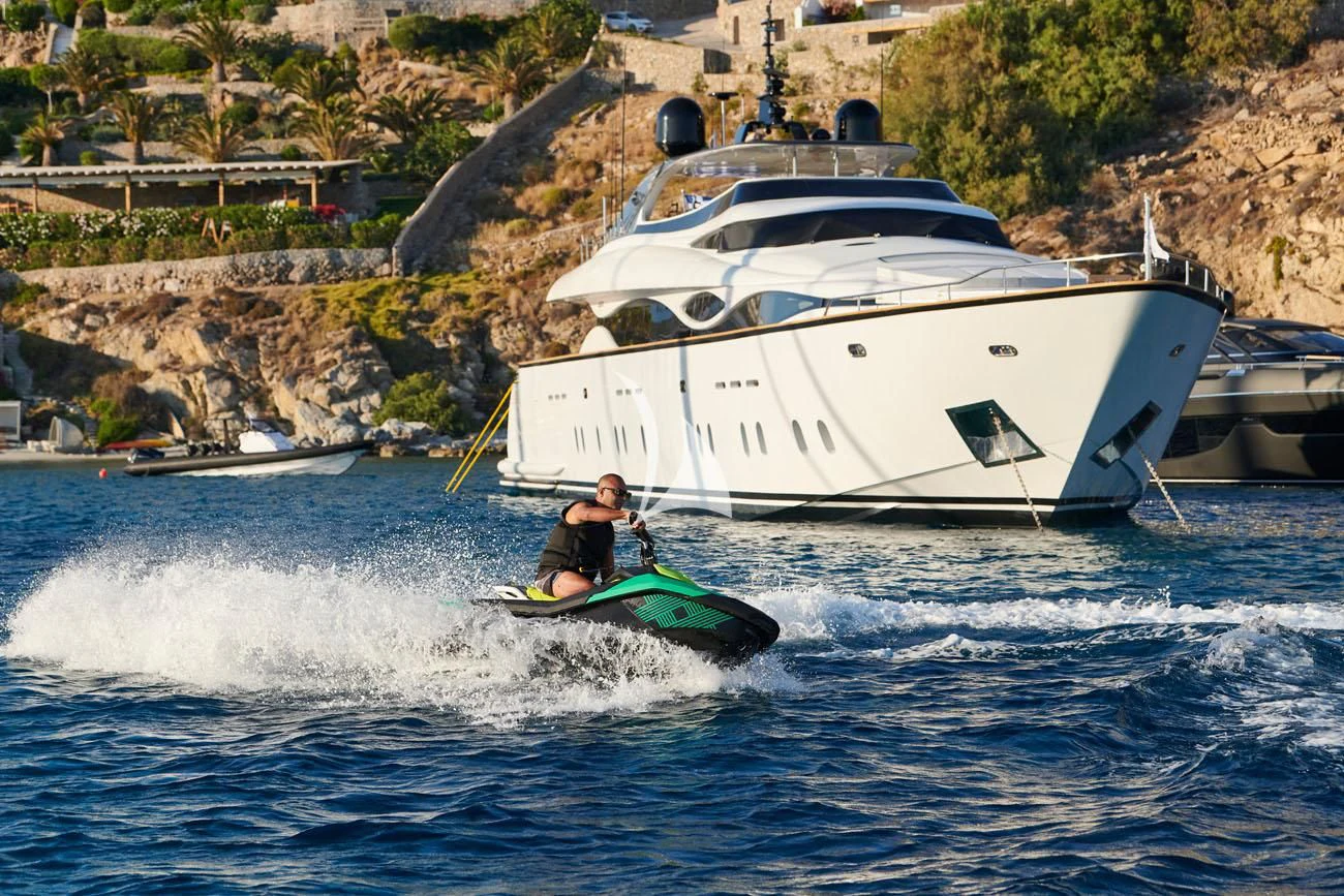a man on a surfboard in the water next to a boat aboard WHITE KNIGHT Yacht for Sale