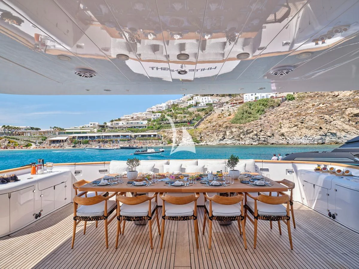 a table set for a meal on a deck overlooking a beach aboard WHITE KNIGHT Yacht for Sale