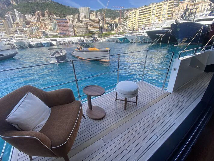 a deck with chairs and a table on it and boats in the water aboard VISSOTTA Yacht for Sale