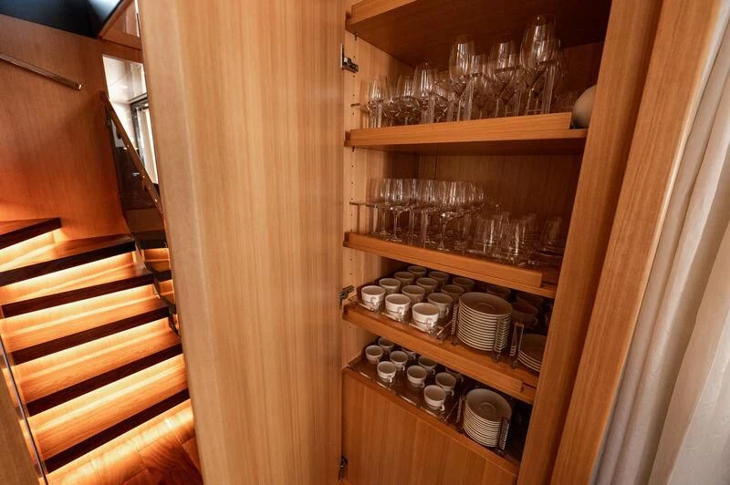 a wooden cabinet with a shelf of wine glasses and a wooden door aboard VISSOTTA Yacht for Sale
