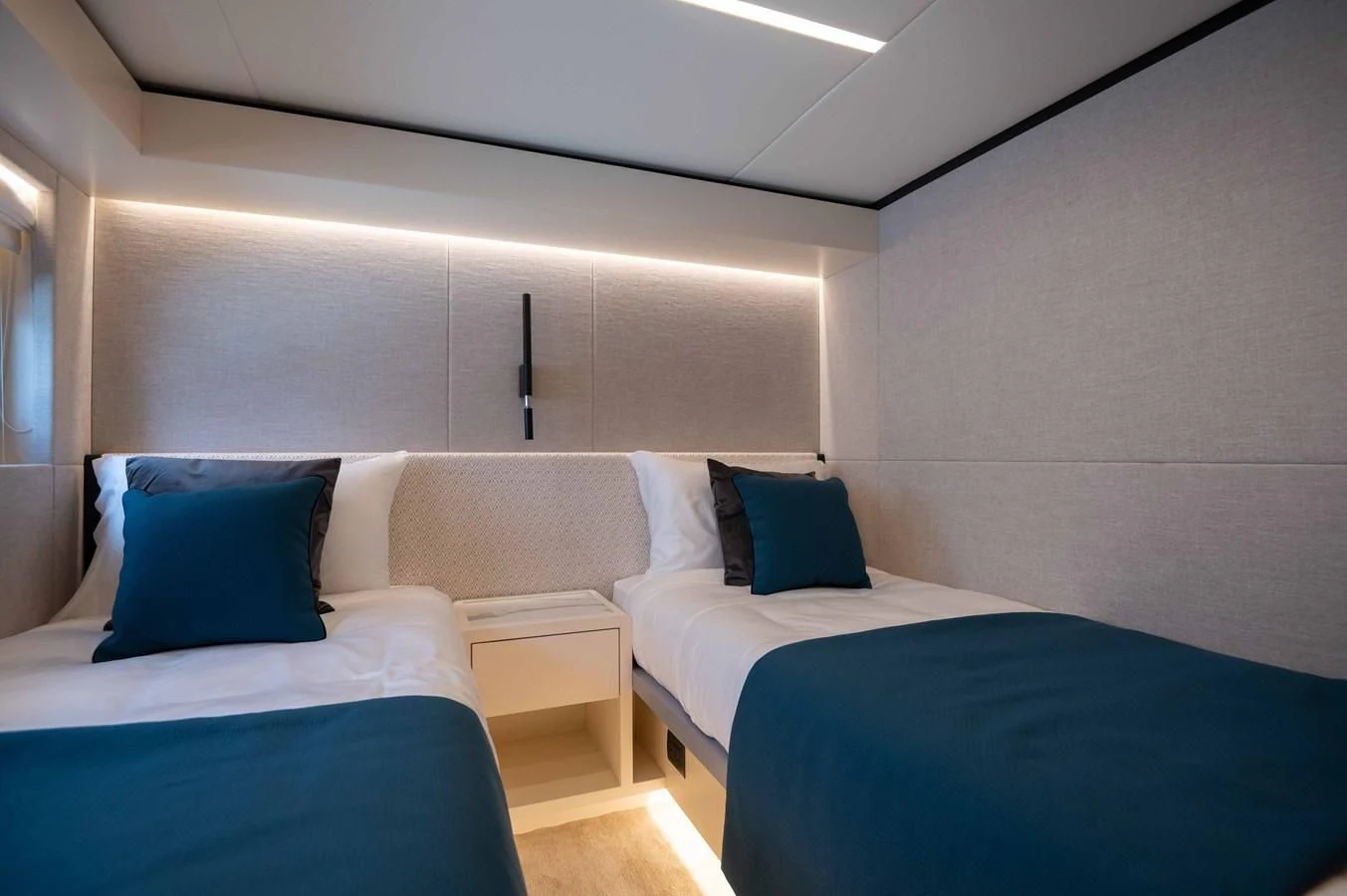 a room with beds and a blue couch aboard NOMAD 70 SUV Yacht for Sale
