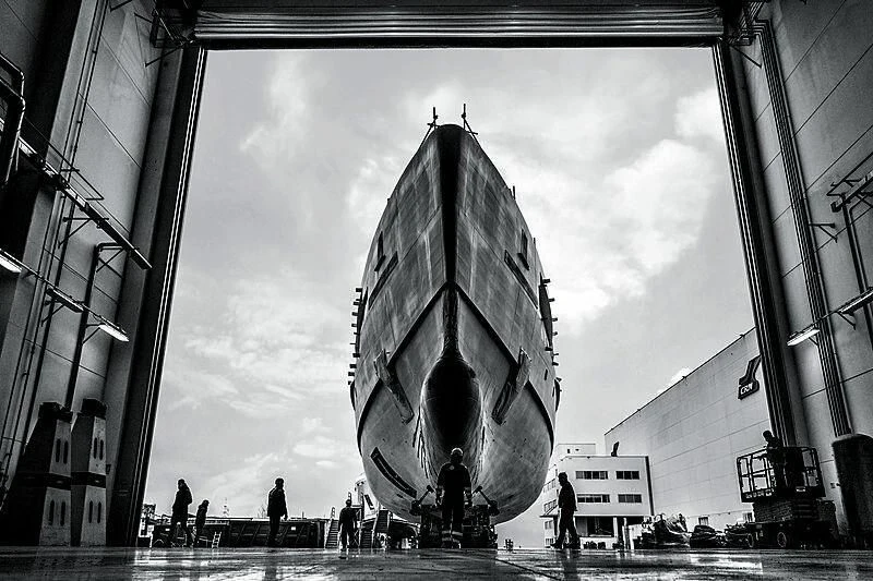 a group of people standing in front of a large round building aboard RIO Yacht for Sale