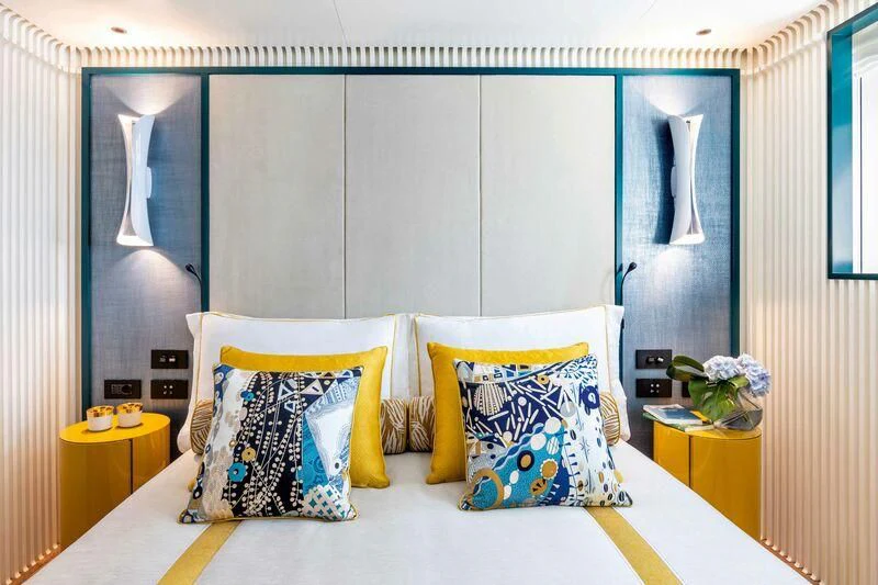 a room with a bed and a table with a flowered pillow aboard RIO Yacht for Sale