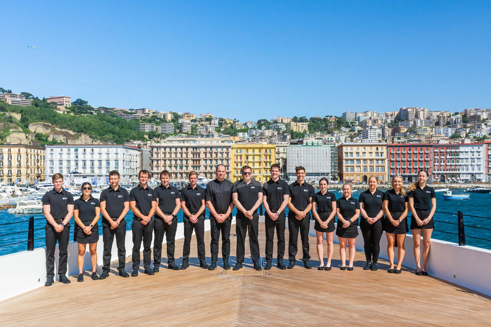 a group of people posing for a photo in front of a city aboard RIO Yacht for Sale