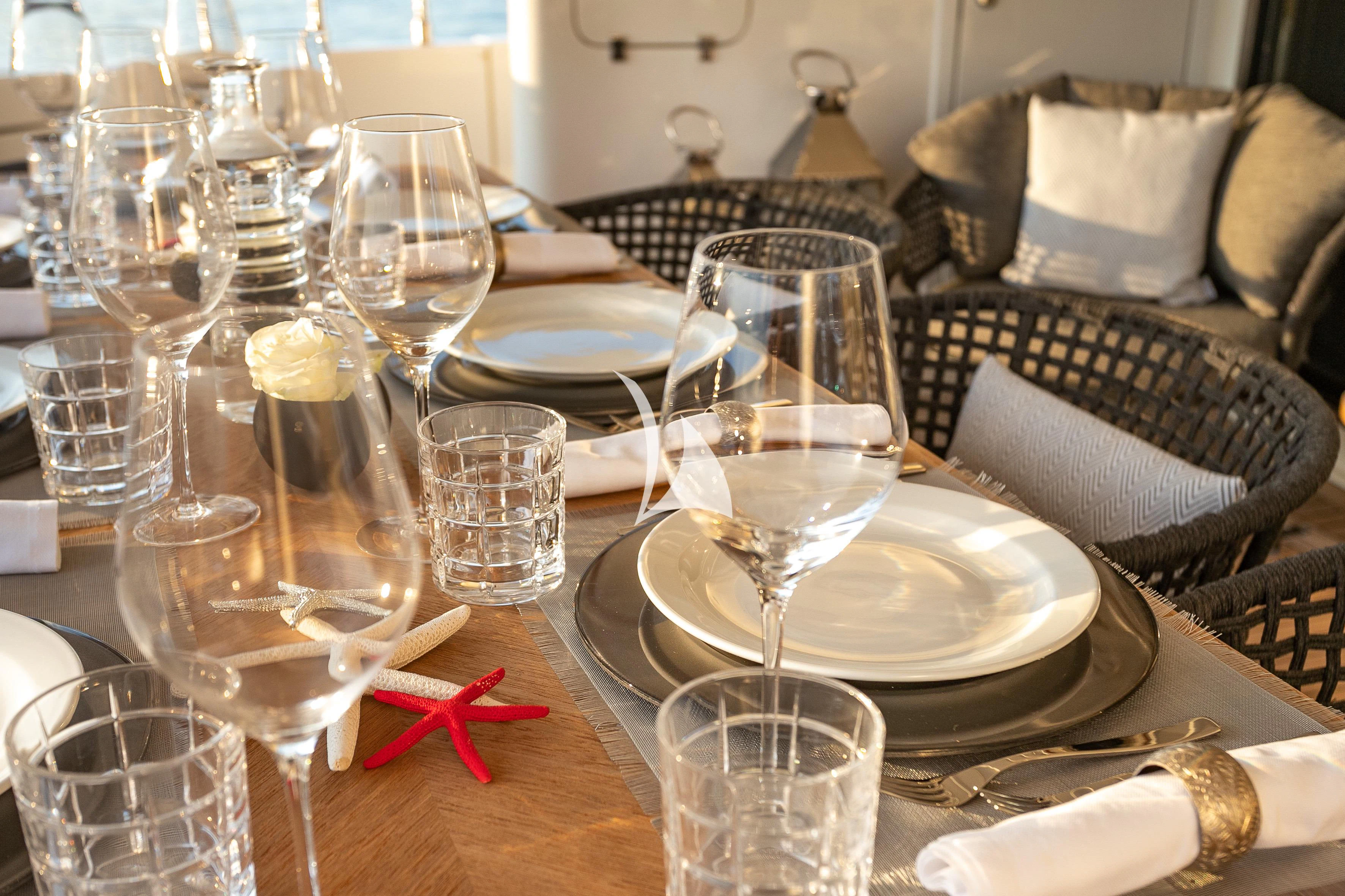 a table with wine glasses and plates aboard ETHNA Yacht for Sale