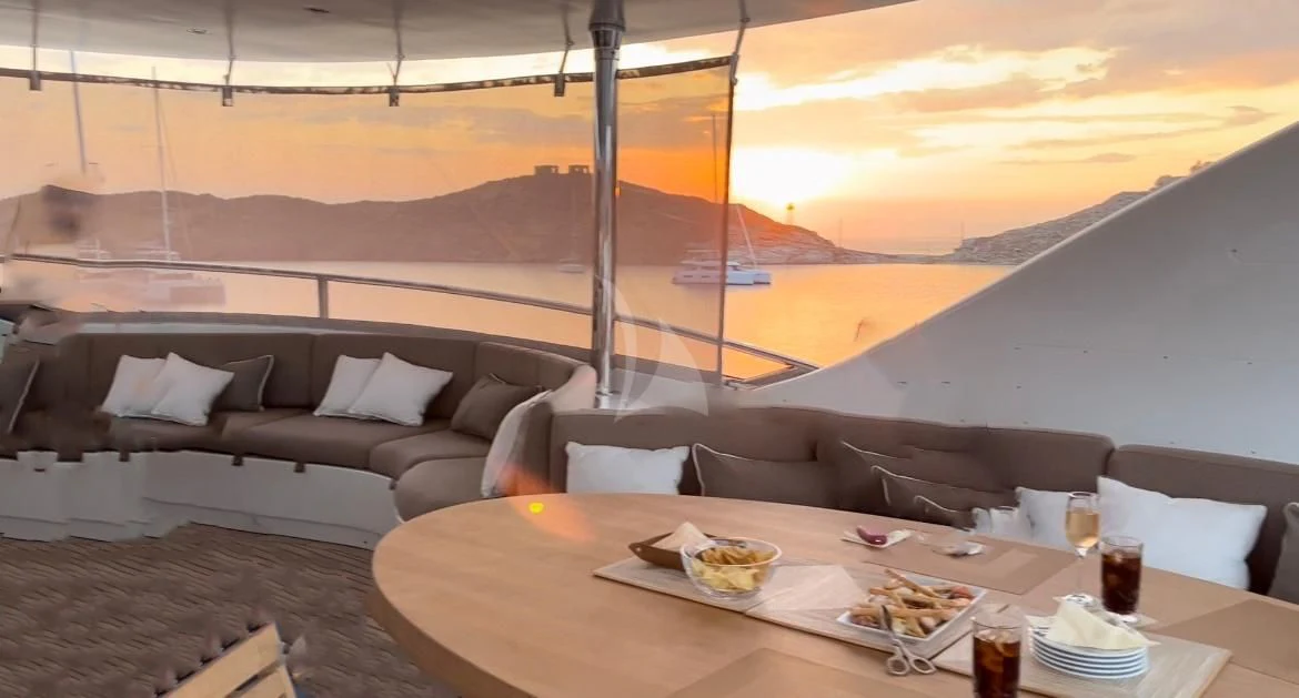 a table with a couch and a large body of water in the background aboard GRANDE AMORE Yacht for Charter