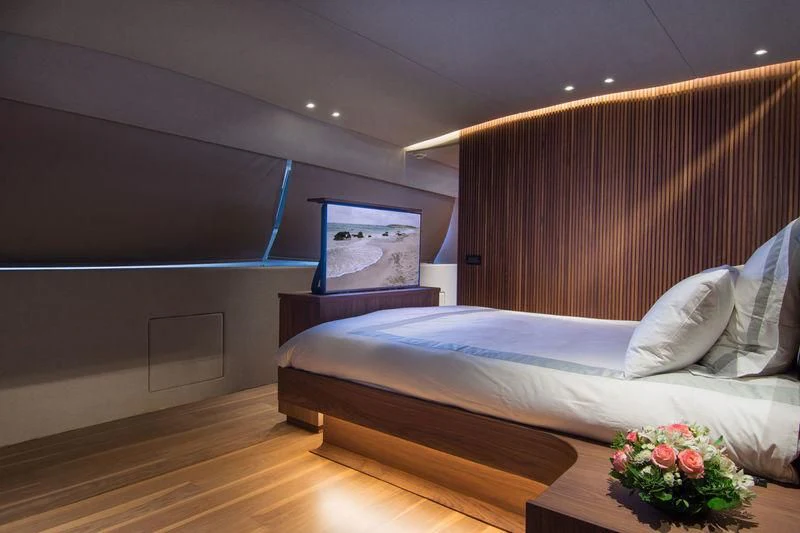 a bed with a white sheet and a table with a flower on it aboard WHISPER V Yacht for Sale