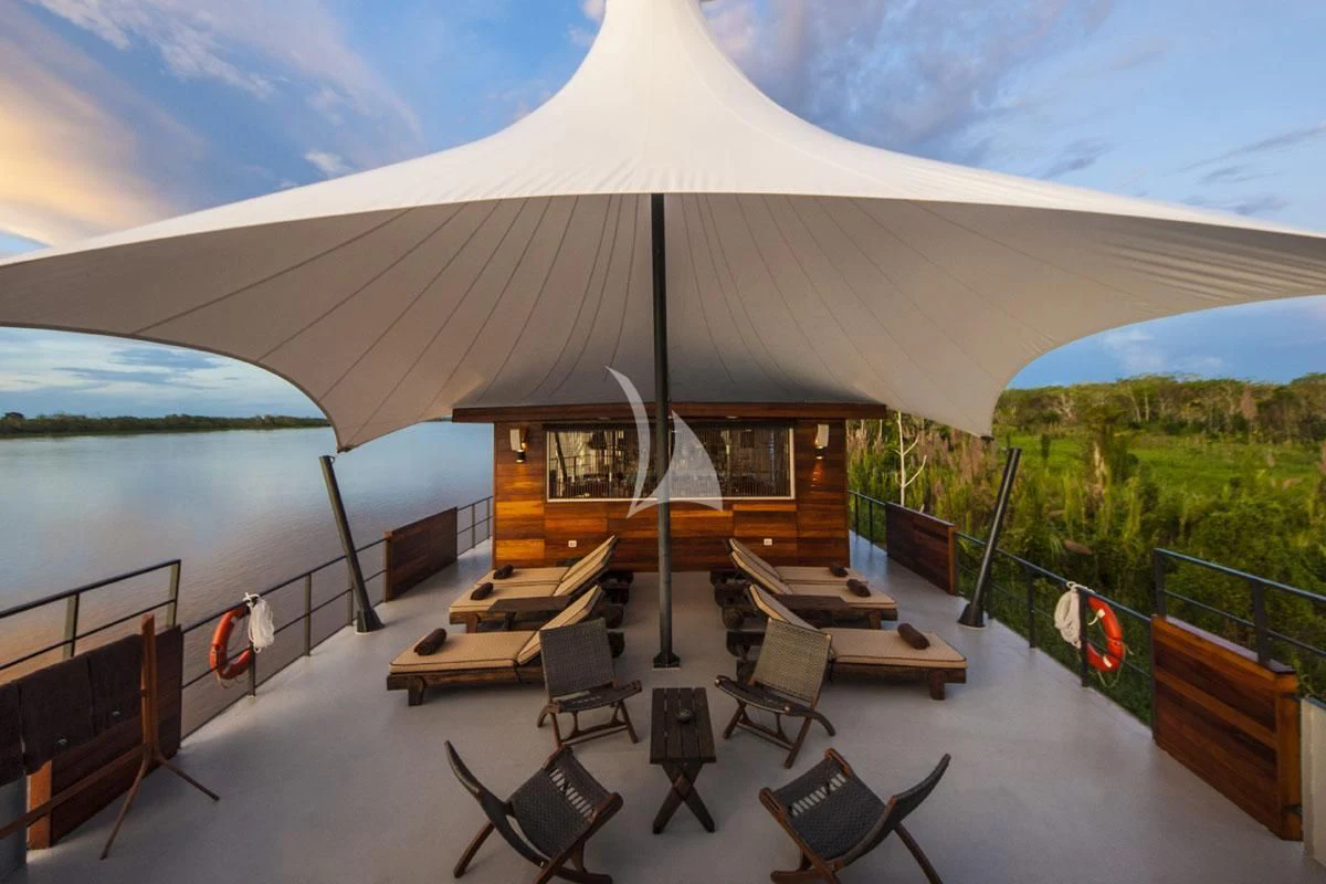 a large white umbrella over a table and chairs on a deck aboard ARIA AMAZON Yacht for Sale