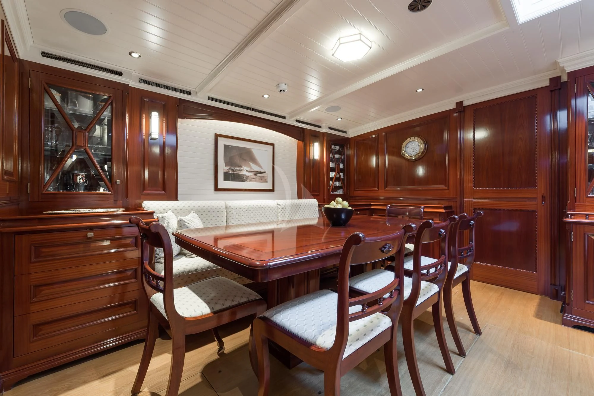 a dining table and chairs in a room with wood cabinets aboard RAINBOW Yacht for Sale