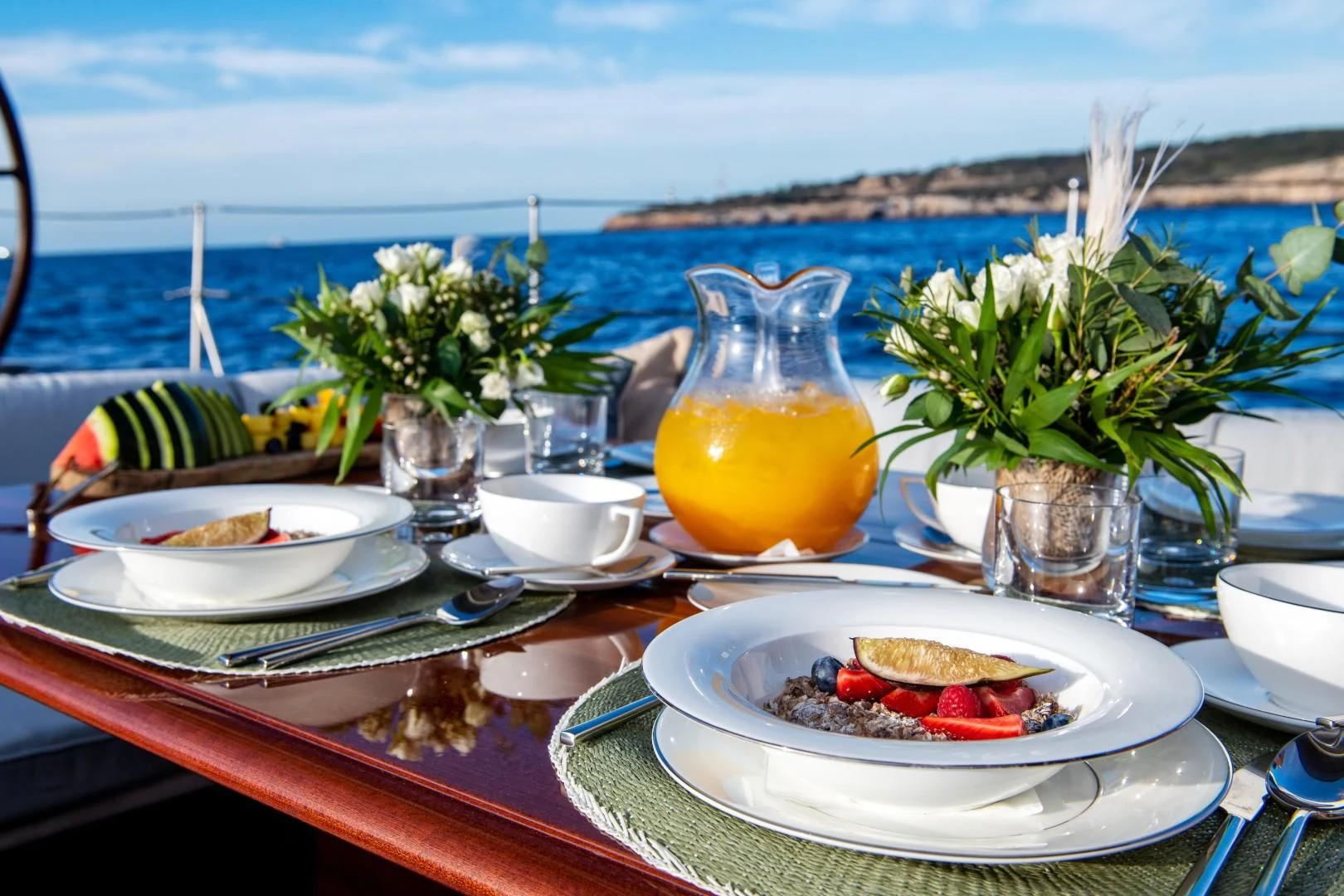 a table with plates and glasses on it with a view of the ocean aboard RAINBOW Yacht for Sale