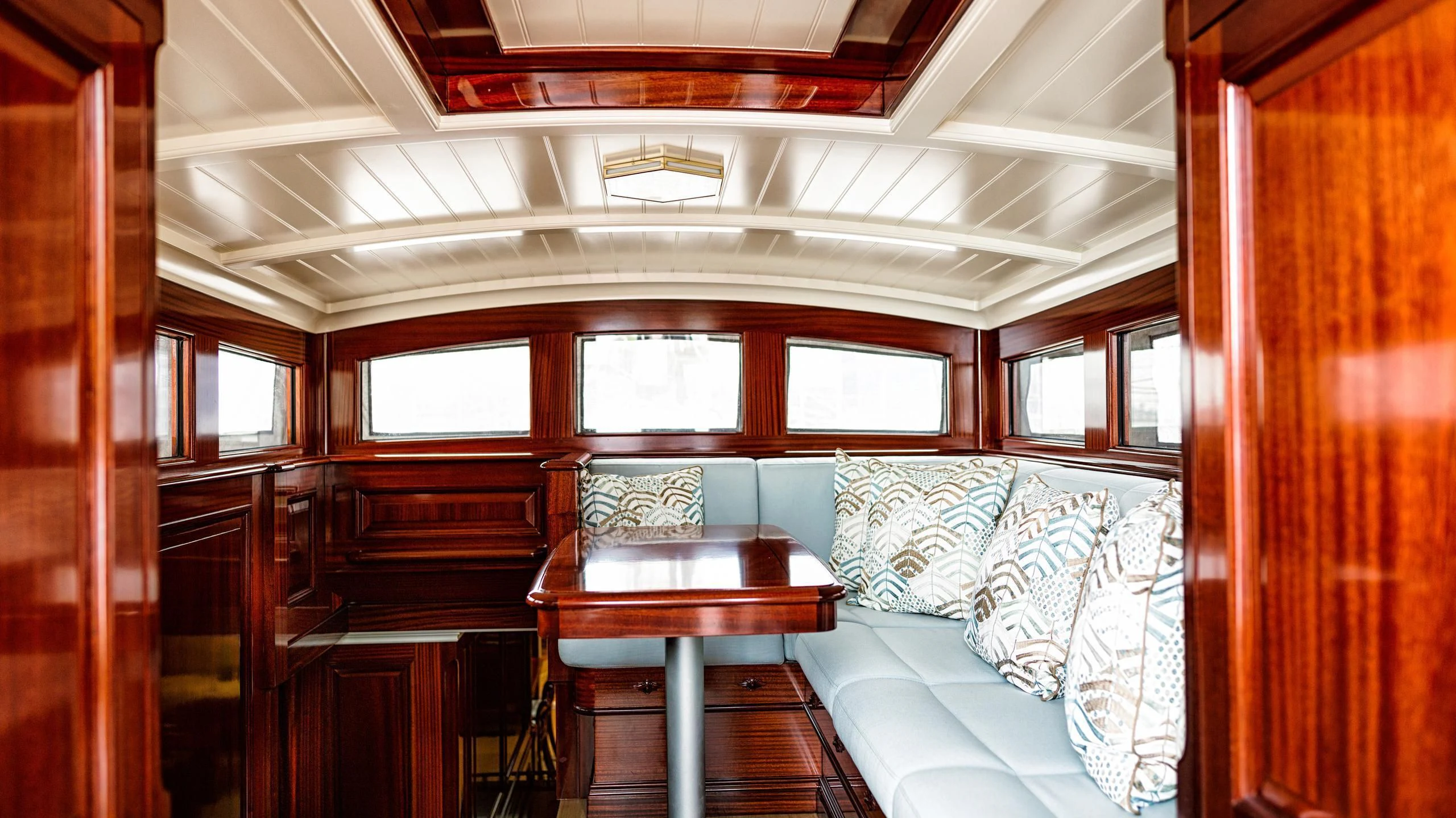 a train car with a table and couches aboard RAINBOW Yacht for Sale